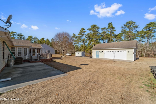 view of yard with a garage, central AC unit, and a shed