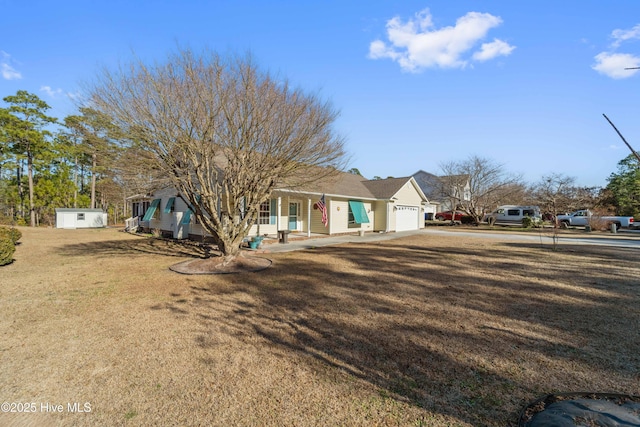 view of front facade with a garage, a front lawn, and a shed