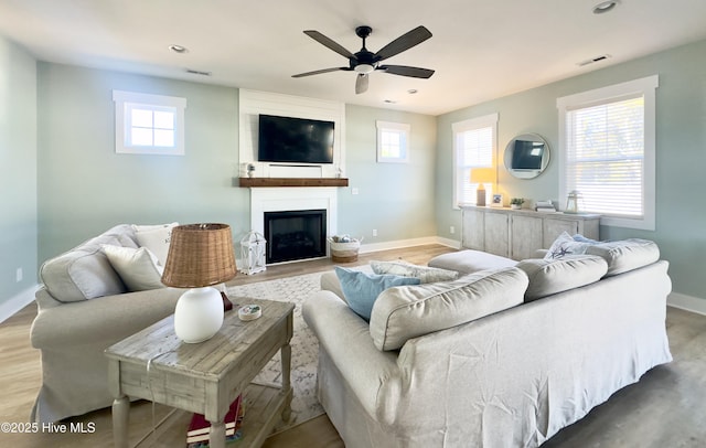 living room featuring light hardwood / wood-style floors, a large fireplace, and ceiling fan