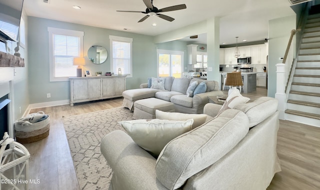 living room featuring ceiling fan, light hardwood / wood-style floors, and a healthy amount of sunlight