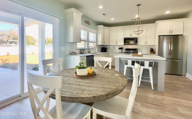 kitchen featuring sink, white cabinetry, a center island, hanging light fixtures, and appliances with stainless steel finishes