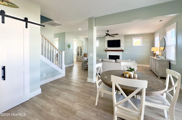 dining room featuring hardwood / wood-style flooring, ceiling fan, and a barn door