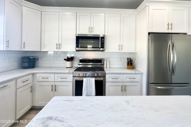 kitchen featuring light stone counters, decorative backsplash, white cabinets, and appliances with stainless steel finishes