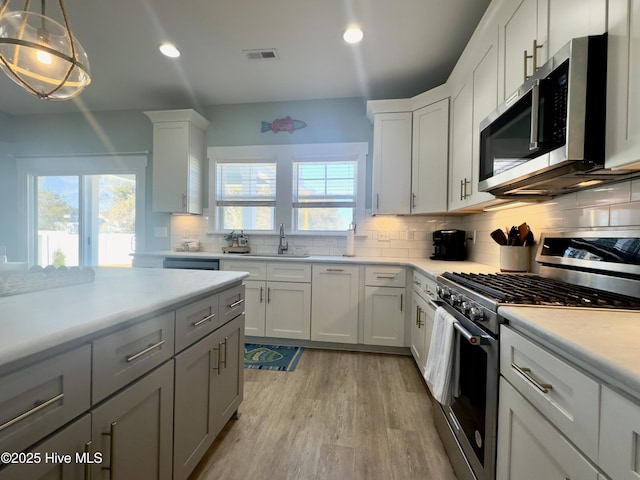 kitchen with white cabinetry, appliances with stainless steel finishes, decorative light fixtures, and sink