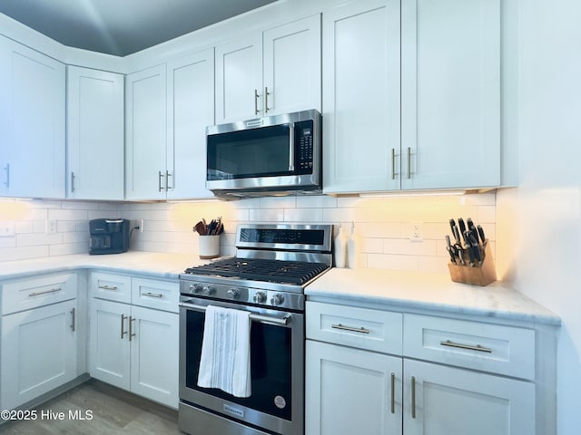 kitchen featuring stainless steel appliances, white cabinets, and decorative backsplash