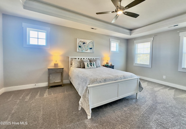 bedroom featuring a raised ceiling, ornamental molding, ceiling fan, and dark carpet