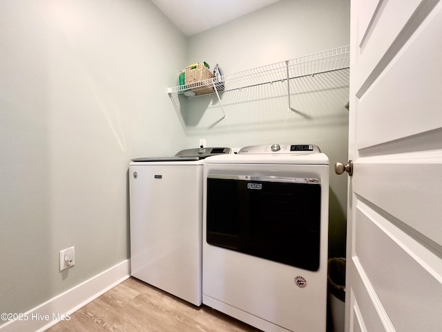 washroom with washing machine and clothes dryer and light wood-type flooring