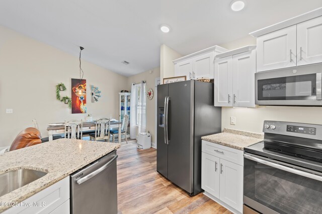 62 NE Dr NW, Calabash, NC 28467 - kitchen featuring appliances with stainless steel finishes, white cabinetry, light wood-style floors, light stone countertops, and vaulted ceiling