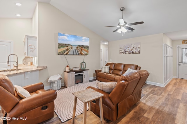 living room with sink, light hardwood / wood-style floors, ceiling fan, and lofted ceiling