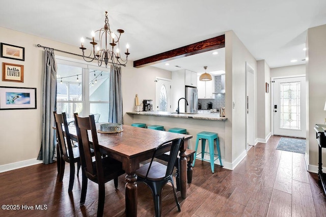 dining area with sink, dark wood-type flooring, beamed ceiling, and a healthy amount of sunlight