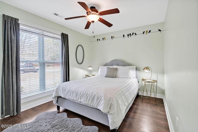 bedroom featuring ceiling fan, dark hardwood / wood-style floors, and multiple windows