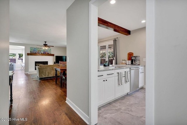 bar with beamed ceiling, a fireplace, dishwasher, white cabinetry, and sink