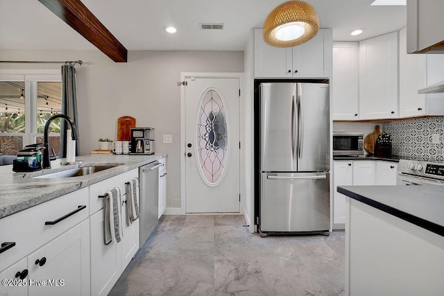 kitchen featuring light stone countertops, appliances with stainless steel finishes, white cabinetry, sink, and beam ceiling