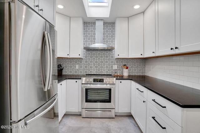 kitchen with wall chimney range hood, stainless steel appliances, and white cabinetry