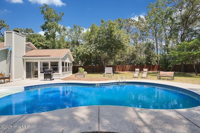 view of pool with a patio area, a grill, a sunroom, and a lawn