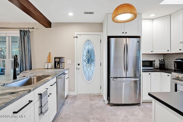 kitchen featuring white cabinets, appliances with stainless steel finishes, and beamed ceiling