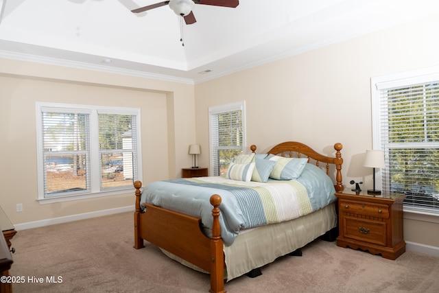 bedroom featuring ceiling fan, light colored carpet, ornamental molding, and a raised ceiling