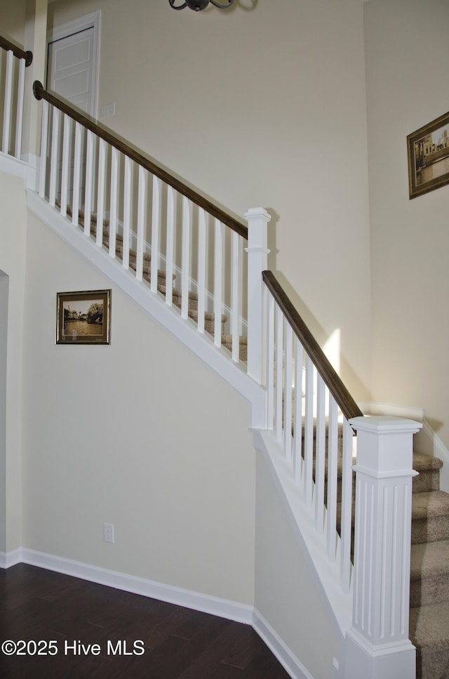 staircase featuring hardwood / wood-style flooring and a towering ceiling