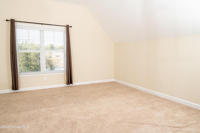 additional living space featuring light colored carpet and lofted ceiling