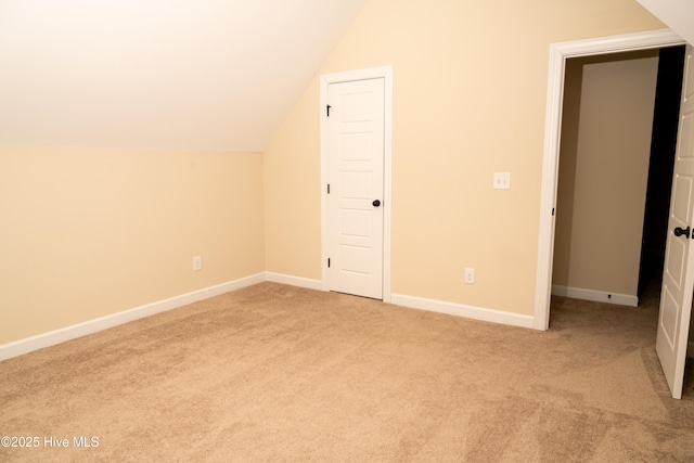 bonus room with vaulted ceiling and light carpet