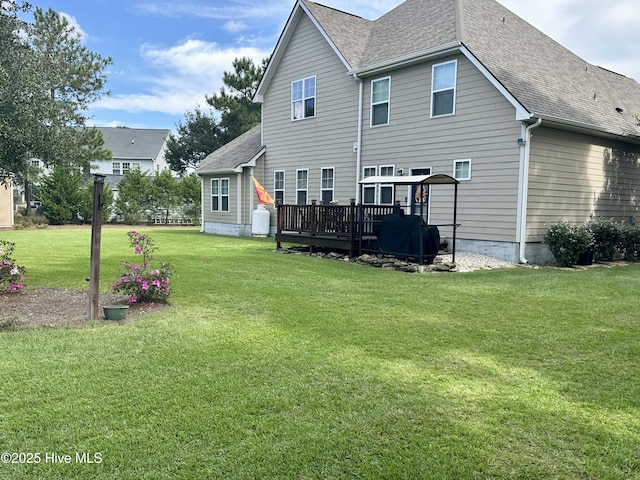 rear view of house featuring a wooden deck and a yard