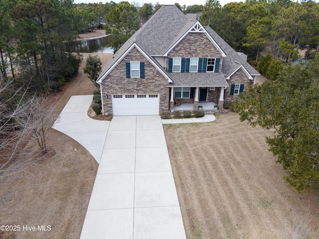 craftsman inspired home with a garage, a water view, a porch, and a front yard