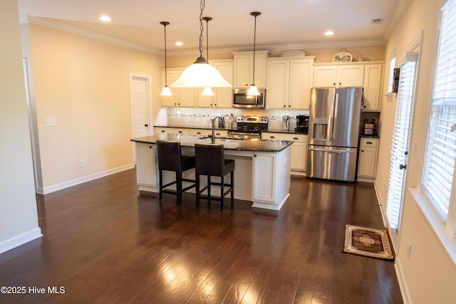 kitchen with stainless steel appliances, dark hardwood / wood-style floors, a center island with sink, decorative light fixtures, and dark stone counters