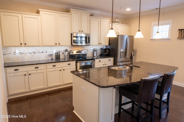 kitchen with sink, appliances with stainless steel finishes, dark hardwood / wood-style flooring, pendant lighting, and a kitchen island with sink