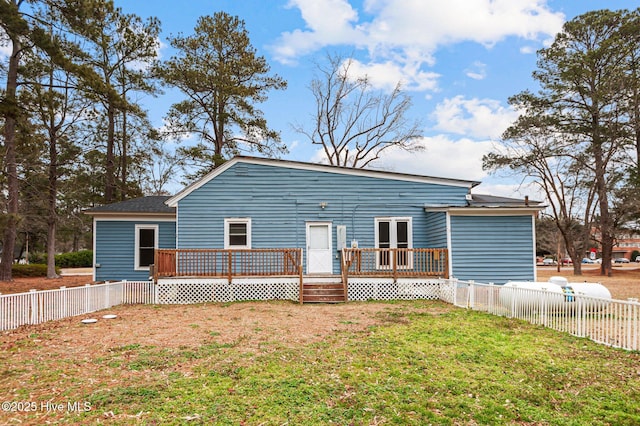 back of house featuring a lawn and a wooden deck