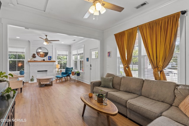 living room with a brick fireplace, crown molding, plenty of natural light, and light hardwood / wood-style floors