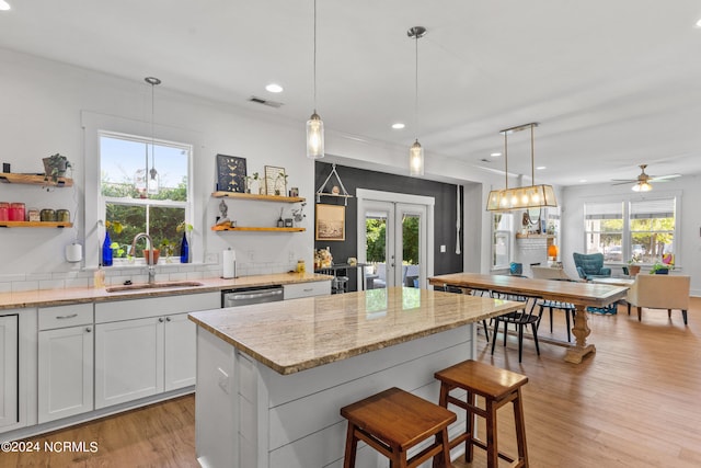 kitchen with decorative light fixtures, sink, and white cabinets