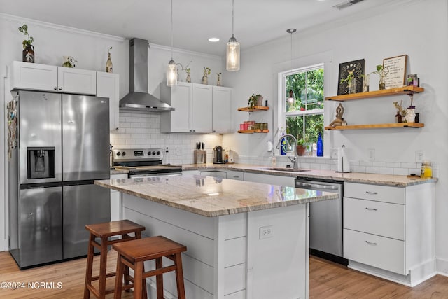 kitchen featuring sink, white cabinets, a center island, stainless steel appliances, and wall chimney exhaust hood