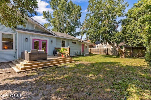 view of yard with an outdoor living space, a deck, and french doors