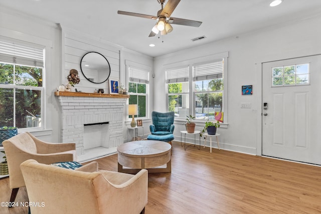 living room with ceiling fan, a fireplace, a healthy amount of sunlight, and light wood-type flooring