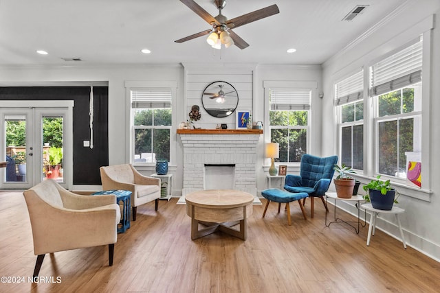 sitting room with ornamental molding, plenty of natural light, a fireplace, and light hardwood / wood-style floors