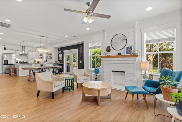 living room featuring ceiling fan, a fireplace, and light hardwood / wood-style floors