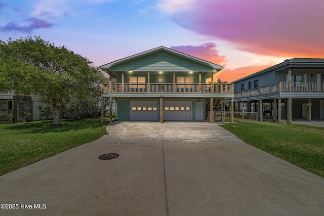 raised beach house with an attached garage, concrete driveway, and a front yard
