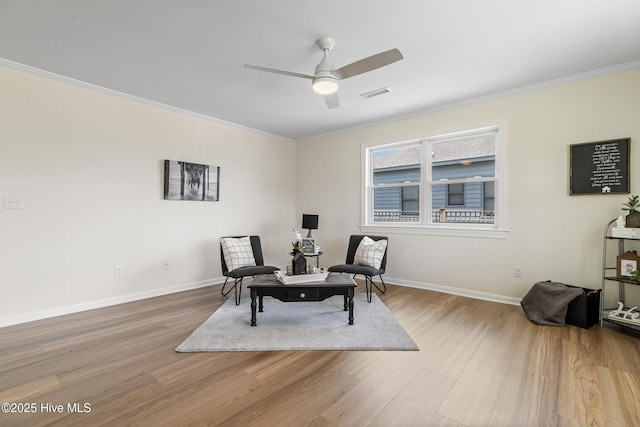 living area with a ceiling fan, ornamental molding, visible vents, wood finished floors, and baseboards