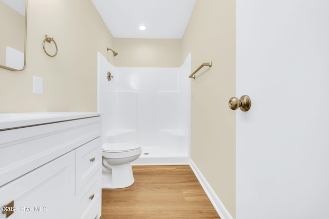 bathroom with toilet, hardwood / wood-style floors, vanity, and walk in shower