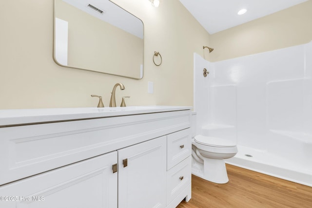 bathroom with hardwood / wood-style flooring, vanity, a shower, and toilet