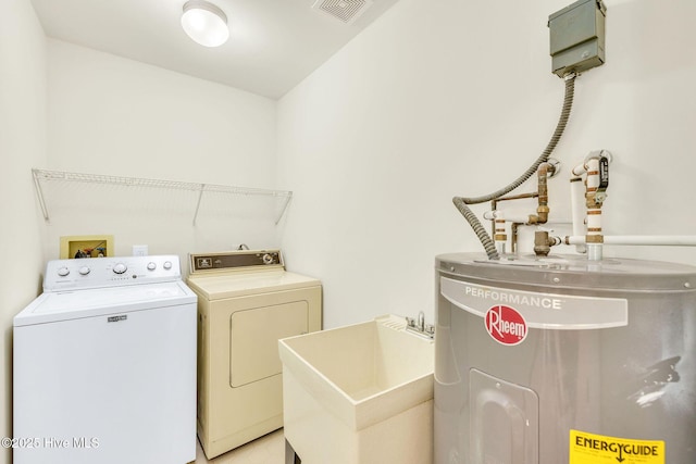 clothes washing area featuring electric water heater, sink, and washer and dryer