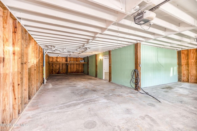 garage with a garage door opener and wood walls