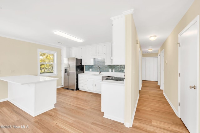 kitchen with sink, stainless steel fridge, light hardwood / wood-style floors, decorative backsplash, and white cabinets