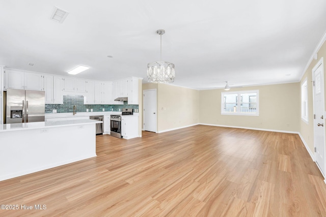 kitchen with pendant lighting, sink, appliances with stainless steel finishes, white cabinets, and decorative backsplash