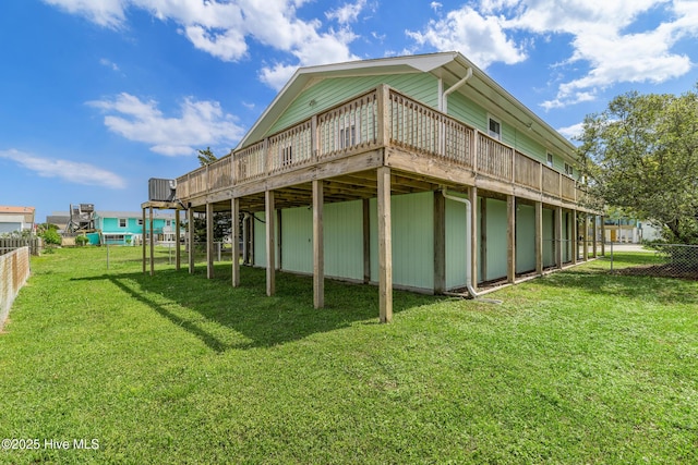 rear view of house with a wooden deck, fence, and a lawn
