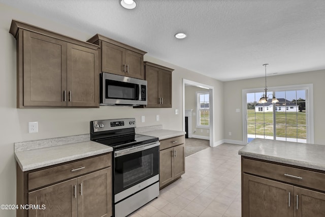 kitchen with dark brown cabinets, a textured ceiling, hanging light fixtures, and stainless steel appliances