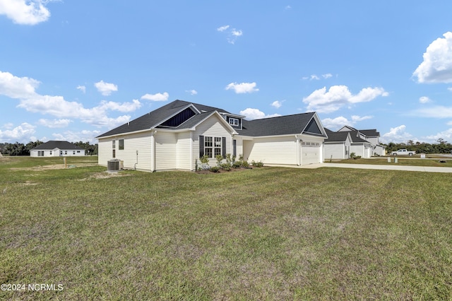 view of front of house featuring a garage, a front yard, and central AC unit