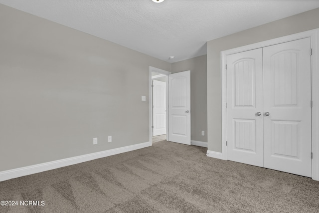 unfurnished bedroom featuring carpet floors, a textured ceiling, and a closet