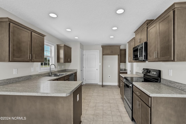 kitchen featuring dark brown cabinets, appliances with stainless steel finishes, sink, light tile patterned floors, and a textured ceiling