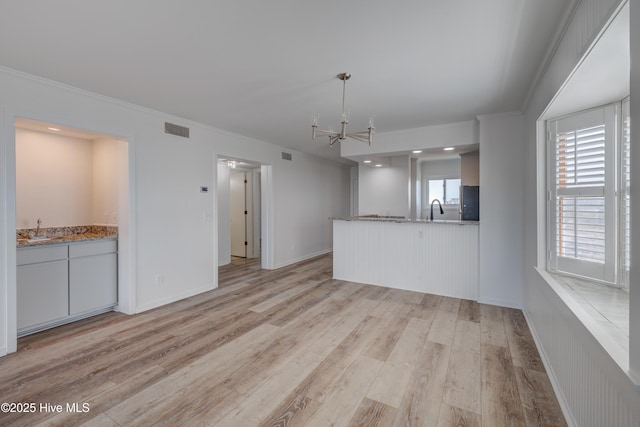 kitchen featuring light wood-style flooring, a notable chandelier, a sink, visible vents, and ornamental molding